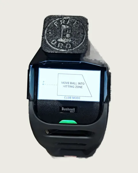 A black 3D-printed hood with a FreeDrop logo cap fitted on top of a launch monitor, whose screen reads Move ball into hitting zone