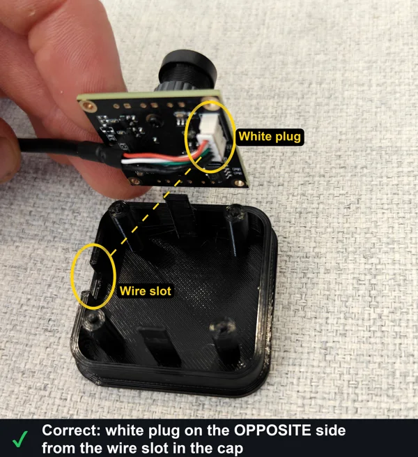 Correct camera orientation: the white plug on the camera board and the wire slot in the cap, ringed in yellow, on opposite sides