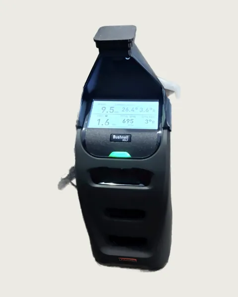 A launch monitor with the hood fitted, its screen showing ball speed, launch angle, spin and carry numbers
